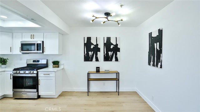 8810 Hewitt Pl Unit 2, Garden Grove, CA 92844 - kitchen featuring appliances with stainless steel finishes, white cabinets, light countertops, light wood finished floors, and a chandelier