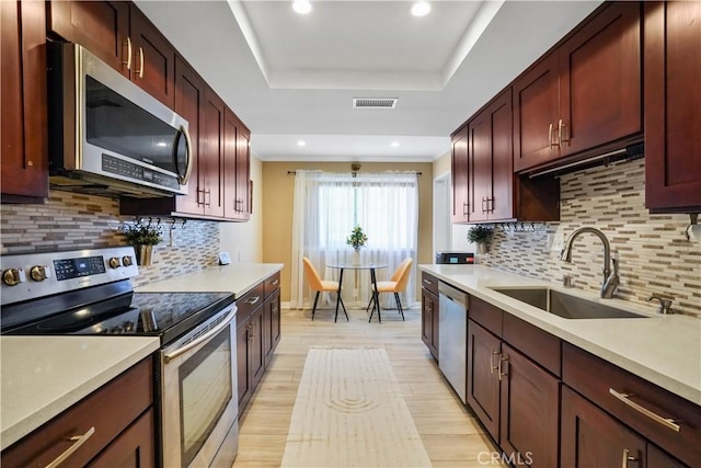 18230 Oxnard St Unit 110, Tarzana, CA 91356 - kitchen featuring appliances with stainless steel finishes, light wood-style flooring, a raised ceiling, light countertops, and reddish brown cabinets