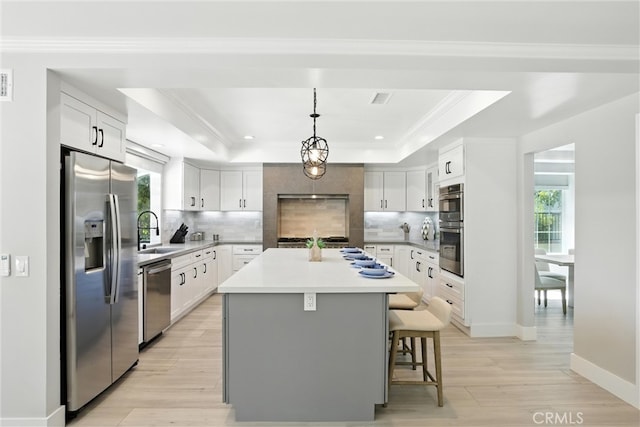20455 Via Canarias, Yorba Linda, CA 92887 - kitchen featuring appliances with stainless steel finishes, a raised ceiling, a breakfast bar, a kitchen island, and tasteful backsplash