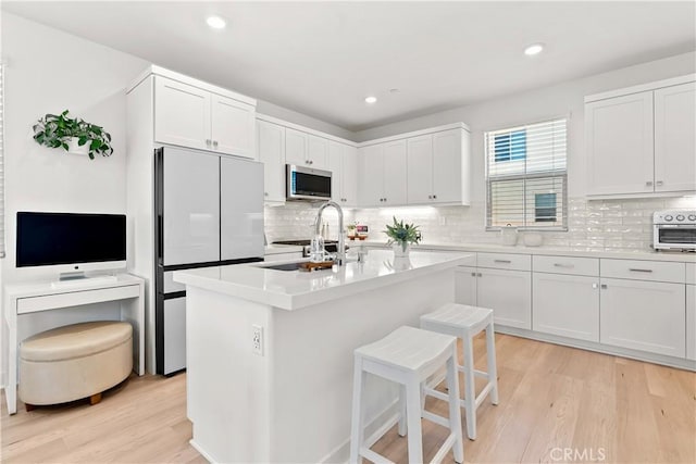 90 Harness Way, Rancho Mission Viejo, CA 92694 - kitchen featuring stainless steel microwave, freestanding refrigerator, light wood-style flooring, decorative backsplash, and a kitchen bar