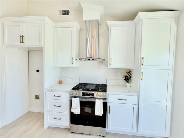 1421 Wildflower St, Rialto, CA 92377 - kitchen with stainless steel range with gas cooktop, wall chimney range hood, white cabinetry, and light wood-style flooring