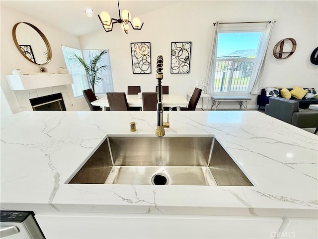 1421 Wildflower St, Rialto, CA 92377 - kitchen with light stone counters, vaulted ceiling, a chandelier, decorative light fixtures, and a premium fireplace