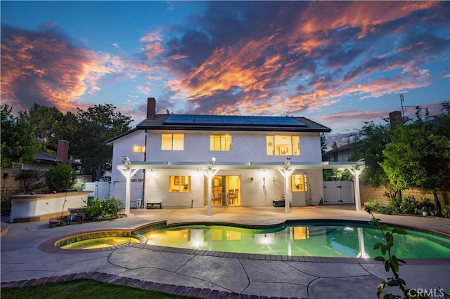 11721 Killimore Ave, Porter Ranch, CA 91326 - back of house at dusk featuring stucco siding, a patio, a chimney, and solar panels
