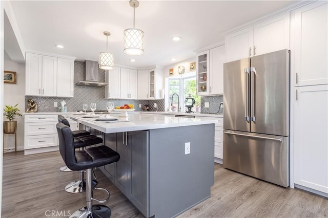 11721 Killimore Ave, Porter Ranch, CA 91326 - kitchen with high end refrigerator, wall chimney exhaust hood, a center island, white cabinetry, and recessed lighting