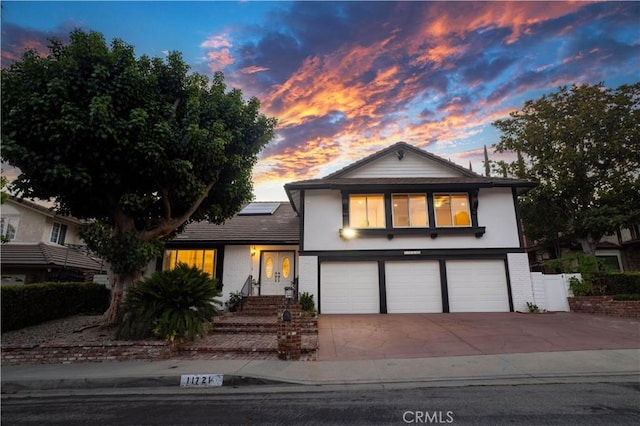 11721 Killimore Ave, Porter Ranch, CA 91326 - tri-level home featuring a garage, roof mounted solar panels, stucco siding, driveway, and brick siding