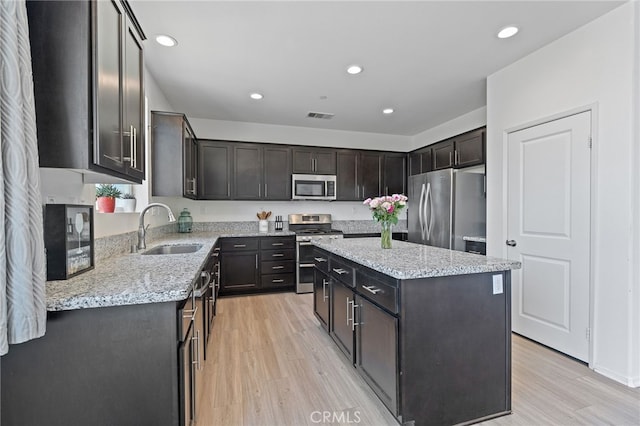 1415 Opal Ct, Beaumont, CA 92223 - kitchen featuring appliances with stainless steel finishes, light wood-type flooring, a kitchen island, recessed lighting, and light stone countertops