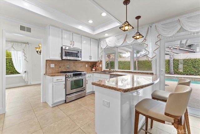 21211 Poston Ln, Huntington Beach, CA 92646 - kitchen with stainless steel appliances, tasteful backsplash, a tray ceiling, white cabinets, and light stone countertops