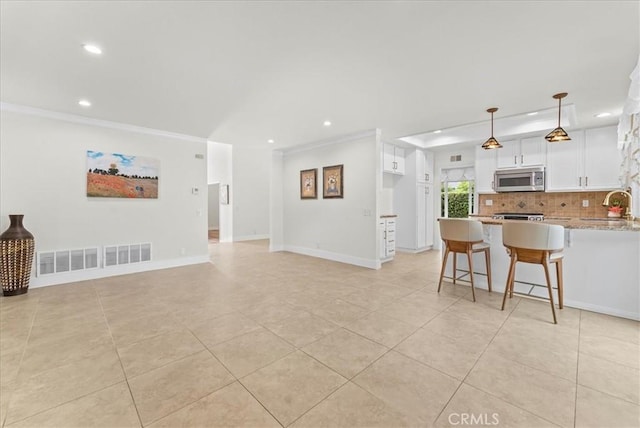 21211 Poston Ln, Huntington Beach, CA 92646 - kitchen with stainless steel microwave, recessed lighting, decorative backsplash, a peninsula, and white cabinetry