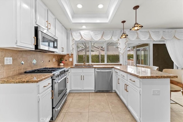 21211 Poston Ln, Huntington Beach, CA 92646 - kitchen with appliances with stainless steel finishes, a tray ceiling, ornamental molding, a peninsula, and recessed lighting
