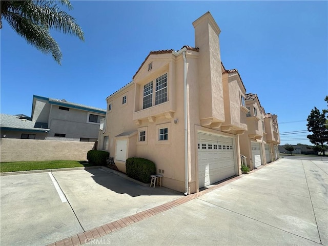 8655 Moody St, Cypress, CA 90630 - view of side of home featuring stucco siding, a garage, and a tile roof