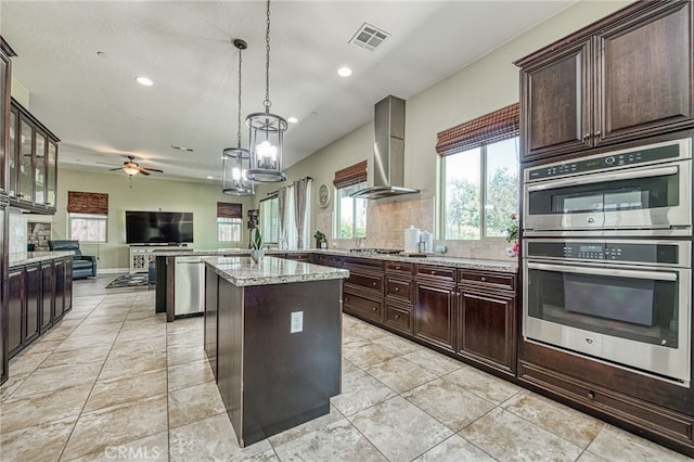6626 W Alluvial Ave, Fresno, CA 93722 - kitchen with stainless steel appliances, wall chimney range hood, a ceiling fan, open floor plan, and light stone counters