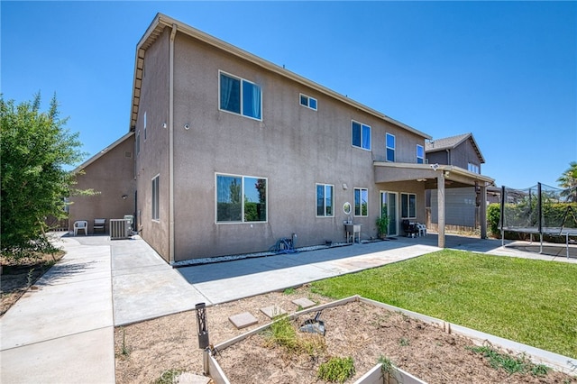 6626 W Alluvial Ave, Fresno, CA 93722 - rear view of house featuring a trampoline, a patio, and stucco siding