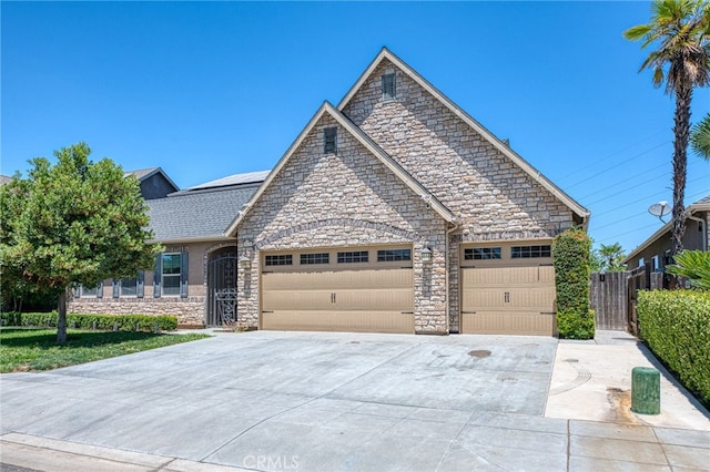 6626 W Alluvial Ave, Fresno, CA 93722 - view of front facade featuring stone siding, an attached garage, solar panels, and driveway