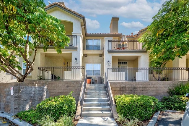 15034 Ocaso Ave, La Mirada, CA 90638 - view of front of house featuring a chimney, stucco siding, a balcony, stairs, and a tile roof