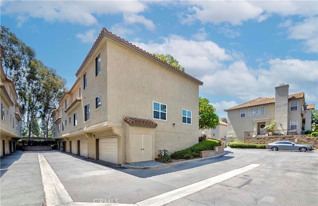 15034 Ocaso Ave, La Mirada, CA 90638 - view of property exterior with stucco siding, a tiled roof, a garage, and a residential view