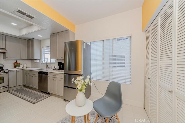 15034 Ocaso Ave, La Mirada, CA 90638 - kitchen featuring appliances with stainless steel finishes, gray cabinetry, light countertops, under cabinet range hood, and a raised ceiling