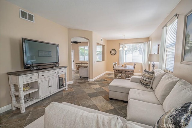 25868 Hammet Cir, Stevenson Ranch, CA 91381 - living area featuring dark stone finish floors, arched walkways, and a chandelier