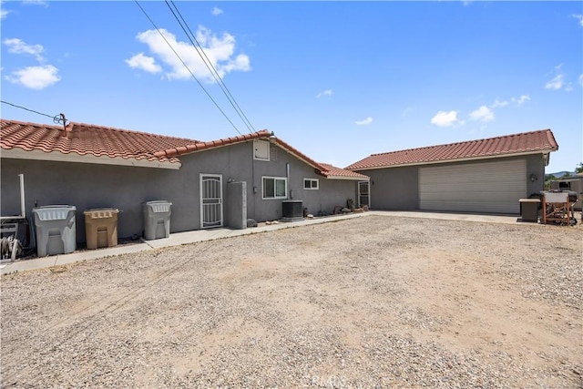 18043 Preston St, Hesperia, CA 92345 - back of house featuring stucco siding, driveway, a tiled roof, and an outdoor structure