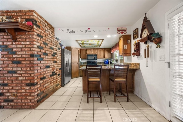 18043 Preston St, Hesperia, CA 92345 - kitchen with stainless steel fridge with ice dispenser, black microwave, a peninsula, brown cabinetry, and light tile patterned floors