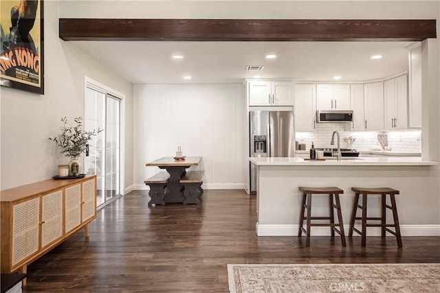 26616 Balerna Dr, Saugus, CA 91350 - kitchen with stainless steel appliances, dark wood-style flooring, beamed ceiling, white cabinets, and a peninsula