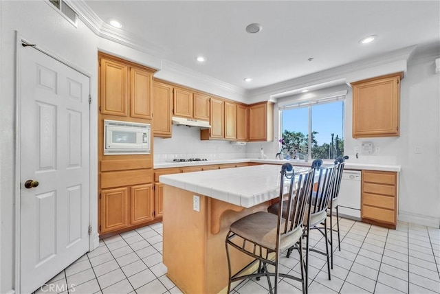 16461 Medinah St, Fontana, CA 92336 - kitchen with white appliances, under cabinet range hood, a center island, light tile patterned flooring, and ornamental molding