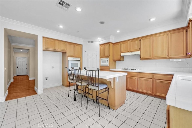16461 Medinah St, Fontana, CA 92336 - kitchen featuring white appliances, under cabinet range hood, light countertops, a kitchen bar, and light tile patterned flooring