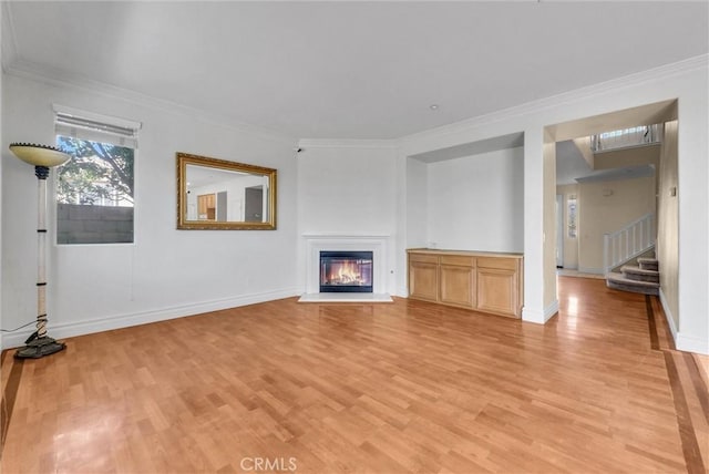16461 Medinah St, Fontana, CA 92336 - unfurnished living room with light wood-style flooring, crown molding, a glass covered fireplace, and stairs