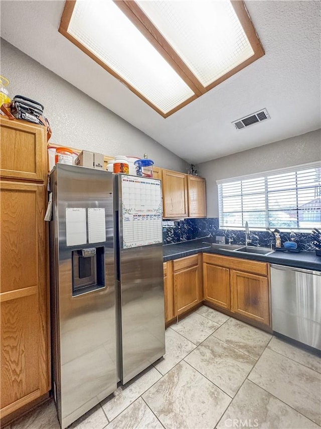 204 Shaded Palm, Blythe, CA 92225 - kitchen with appliances with stainless steel finishes, decorative backsplash, vaulted ceiling, dark countertops, and brown cabinetry