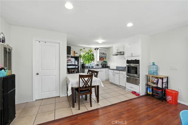 711 E 118th St, Los Angeles, CA 90059 - kitchen with stainless steel oven, a warming drawer, white cabinets, under cabinet range hood, and dark countertops