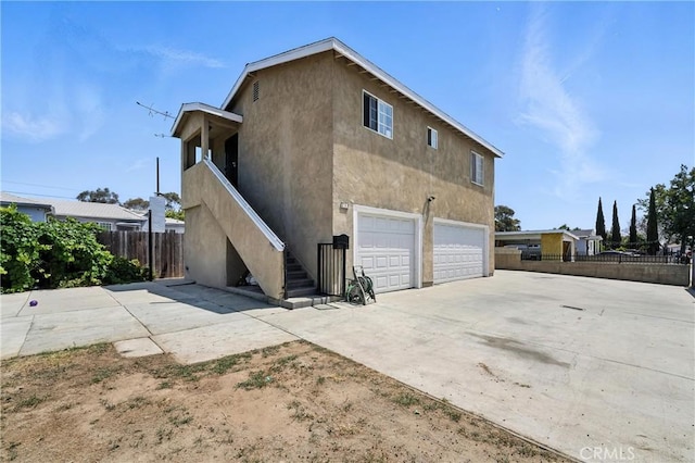 711 E 118th St, Los Angeles, CA 90059 - view of home's exterior featuring stairway, a garage, stucco siding, and driveway