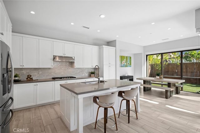 152 Plum Lily, Irvine, CA 92618 - kitchen featuring under cabinet range hood, freestanding refrigerator, light wood-style flooring, backsplash, and white cabinetry