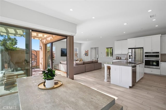 152 Plum Lily, Irvine, CA 92618 - kitchen featuring stainless steel appliances, white cabinetry, light wood-style floors, recessed lighting, and a breakfast bar