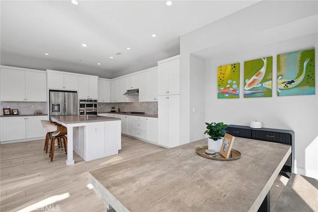 152 Plum Lily, Irvine, CA 92618 - kitchen with stainless steel refrigerator with ice dispenser, under cabinet range hood, backsplash, white cabinetry, and recessed lighting