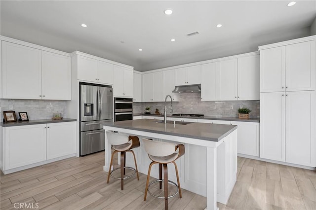 152 Plum Lily, Irvine, CA 92618 - kitchen with stainless steel appliances, dark countertops, under cabinet range hood, recessed lighting, and decorative backsplash