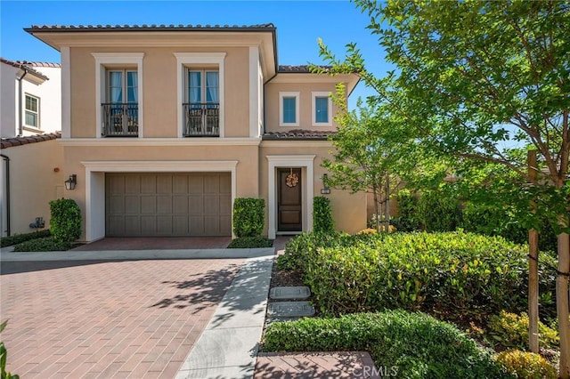 152 Plum Lily, Irvine, CA 92618 - view of front facade with decorative driveway, a garage, stucco siding, a tiled roof, and a balcony