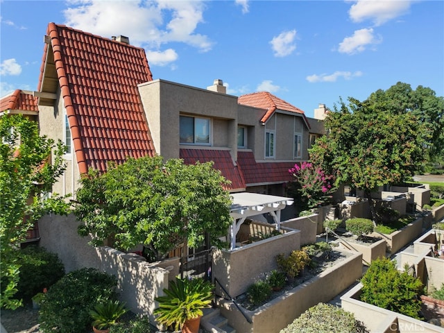 17910 River Cir Unit 1, Canyon Country, CA 91387 - back of property featuring a chimney, a tiled roof, a vegetable garden, and stucco siding