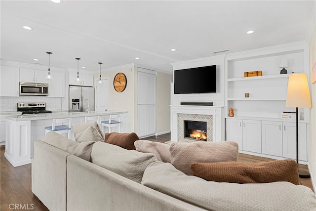 17700 Palo Verde Ave, Cerritos, CA 90703 - living room featuring wood finished floors, a tiled fireplace, recessed lighting, ornamental molding, and built in features
