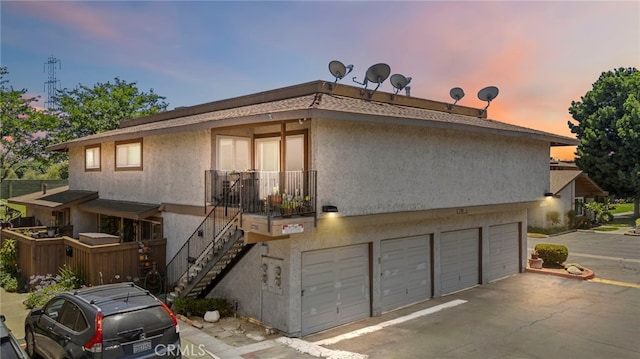 17700 Palo Verde Ave, Cerritos, CA 90703 - back of property at dusk featuring stairs, an attached garage, and stucco siding