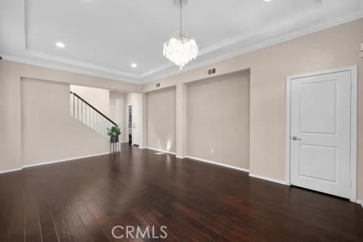 252 W Tulip Tree Ave, Orange, CA 92865 - unfurnished living room with hardwood / wood-style floors, a chandelier, ornamental molding, stairway, and a raised ceiling