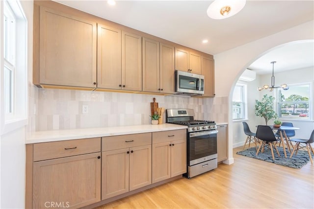 10536 La Mirada Blvd, Whittier, CA 90604 - kitchen featuring stainless steel appliances, arched walkways, decorative backsplash, light countertops, and light wood-style floors