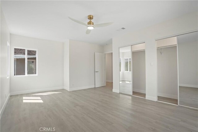 1230 Spazier Ave, Glendale, CA 91201 - unfurnished bedroom featuring multiple closets, light wood finished floors, a ceiling fan, and multiple windows