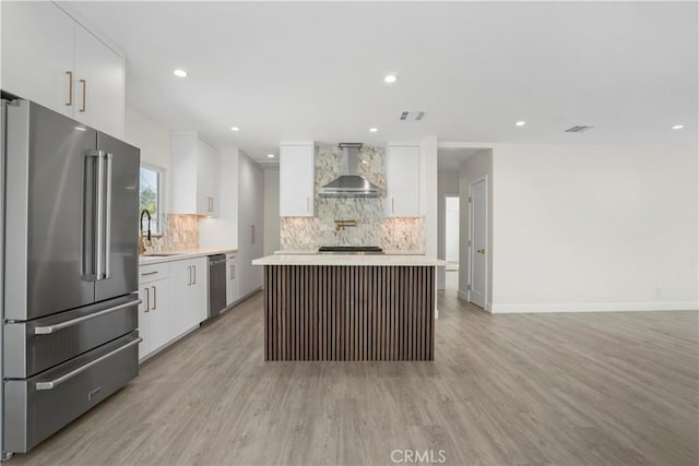 1230 Spazier Ave, Glendale, CA 91201 - kitchen with appliances with stainless steel finishes, wall chimney range hood, decorative backsplash, light wood-type flooring, and light countertops