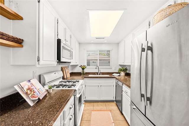 1105 W Calle De La Luna Unit 4, Azusa, CA 91702 - kitchen featuring stainless steel appliances, open shelves, white cabinetry, light tile patterned floors, and dark stone counters