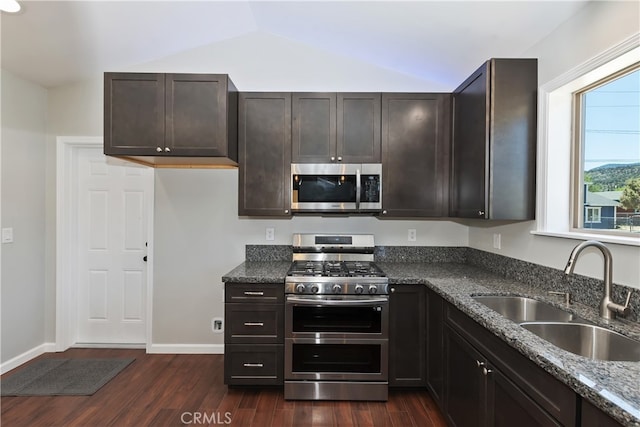 2217 Juniper Ln, Big Bear City, CA 92314 - kitchen with stainless steel appliances, dark wood-style flooring, dark stone countertops, vaulted ceiling, and dark brown cabinetry