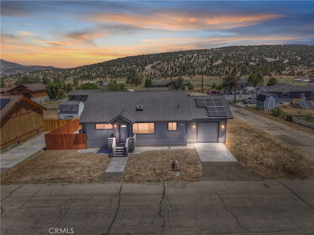 2217 Juniper Ln, Big Bear City, CA 92314 - view of front of property featuring a mountain view, solar panels, a shingled roof, and driveway
