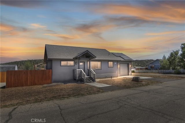 2217 Juniper Ln, Big Bear City, CA 92314 - bungalow-style home featuring a garage, driveway, solar panels, and roof with shingles