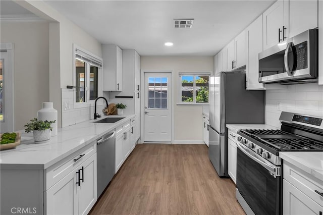 3531 Josie Ave, Long Beach, CA 90808 - kitchen with stainless steel appliances, light wood-style flooring, decorative backsplash, white cabinets, and recessed lighting