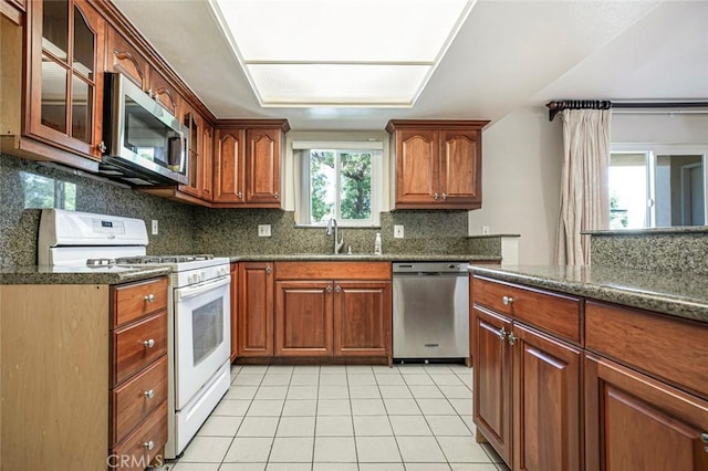 400 N 6th St Unit 202, Burbank, CA 91501 - kitchen featuring appliances with stainless steel finishes, light tile patterned floors, backsplash, and glass insert cabinets