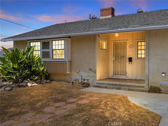 2623 N Parish Pl, Burbank, CA 91504 - exterior entry at dusk with roof with shingles, stucco siding, and a chimney