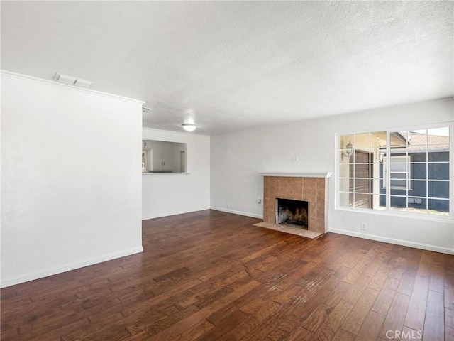 2135 Arden Dr W, Fresno, CA 93703 - unfurnished living room featuring a textured ceiling, wood-type flooring, and a tile fireplace